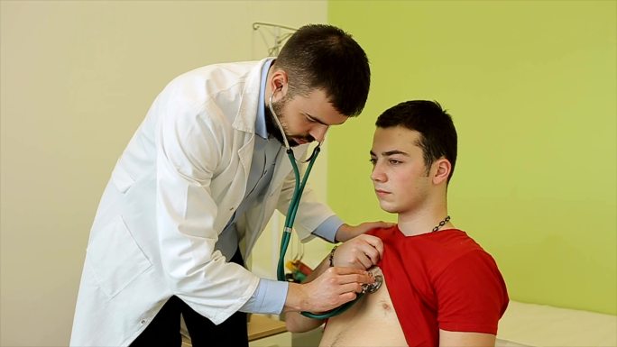 医生用听诊器听一个生病男孩的肺