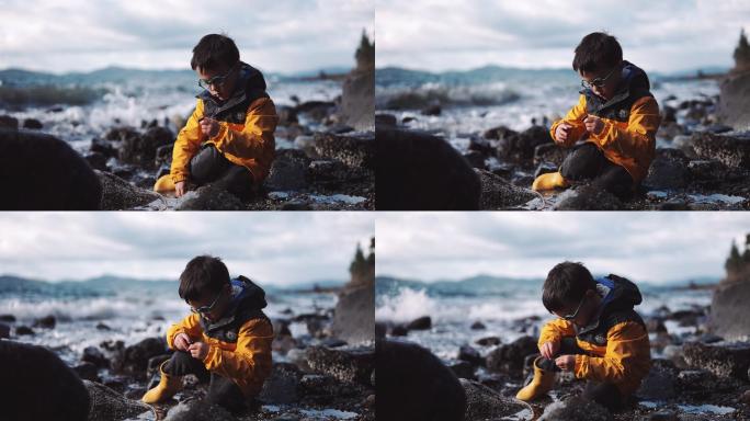 五岁的小男孩在海滩上玩耍，看着海浪拍岸