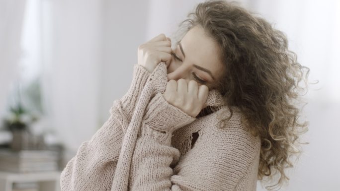 害羞的女人用针织毛衣遮住脸