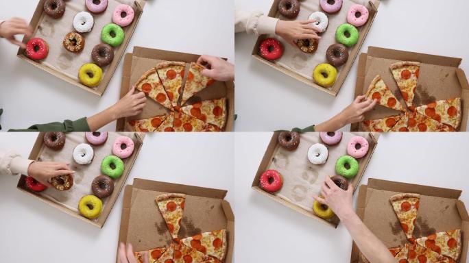 盒子里彩色甜甜圈和披萨的俯视图。与朋友一起吃外卖的概念