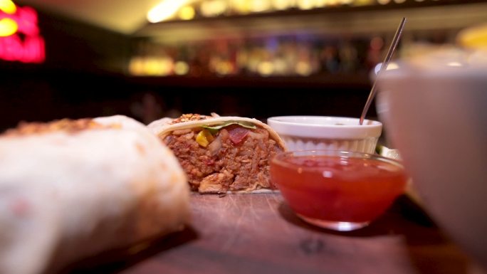 酒吧木板上的碗里放着两个墨西哥牛排煎饼和薯片和酱汁