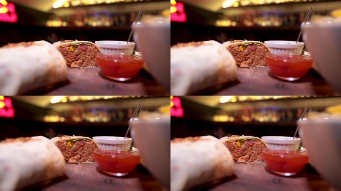 酒吧木板上的碗里放着两个墨西哥牛排煎饼和薯片和酱汁