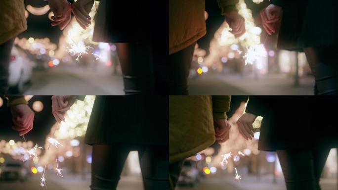 远景：圣诞节期间，一对夫妇在城里散步时手里拿着火花