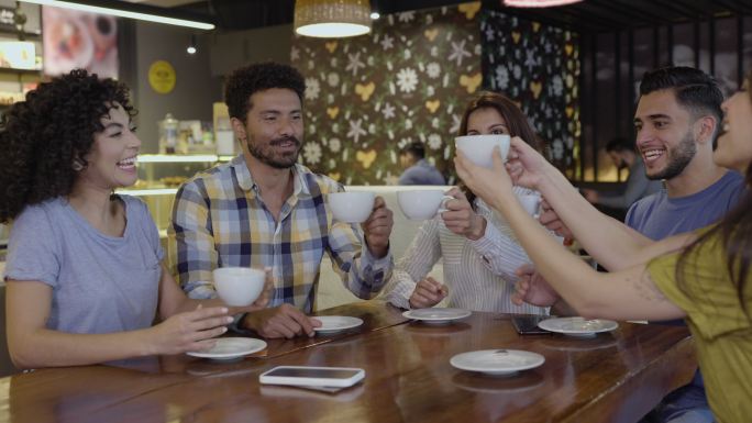 一群形形色色的朋友在咖啡店用咖啡和茶祝酒庆祝