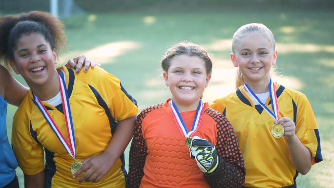 足球队的三个女孩炫耀奖牌