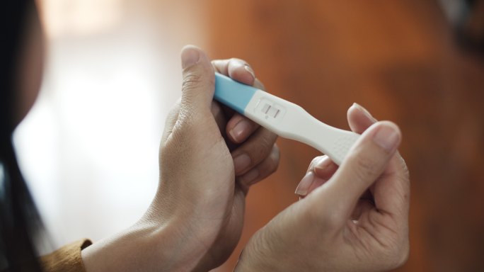 亚洲孕妇在卧室进行妊娠试验呈阳性