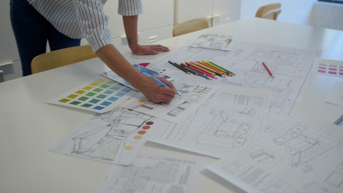 办公室里一位面目全非的室内设计师正在用平板电脑和彩色铅笔绘制不同的草图