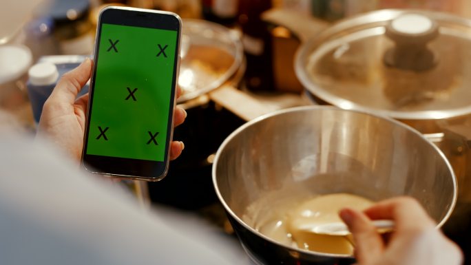 厨师用双锅法和手机在厨房准备酱汁