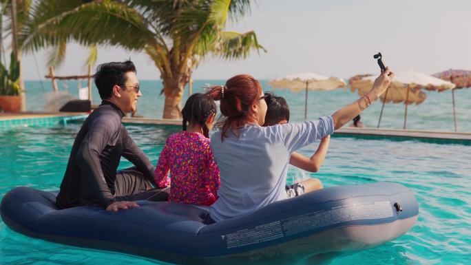 快乐的亚洲大家庭一起玩成游泳池、家庭、度假和旅游的概念。