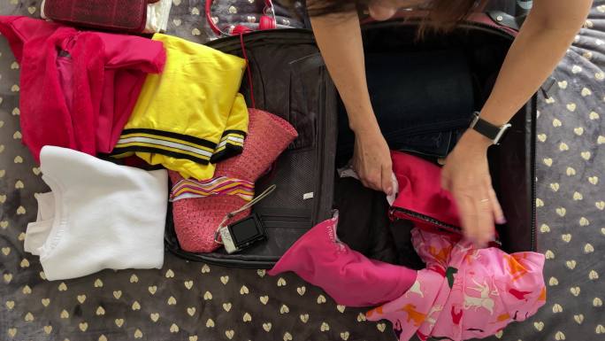 为旅行打包。女性为新的旅行将衣服装进手提箱的特写镜头