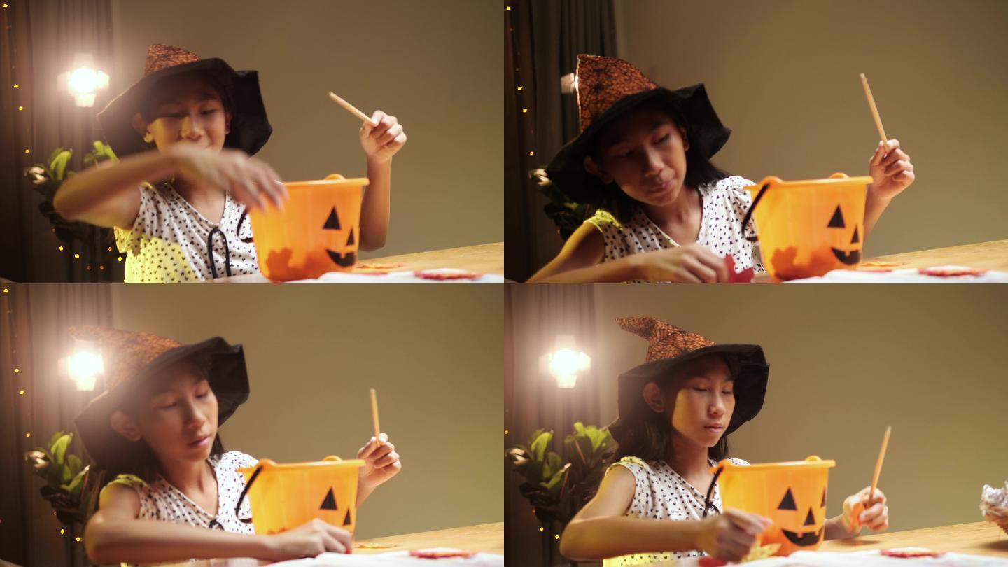 在家里的晚上，一个戴着巫师帽、手持魔杖的亚洲女孩在万圣节的概念游戏中玩耍。