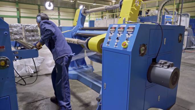 西班牙裔男性工人在层压塑料制造回收生产线上更换层压辊