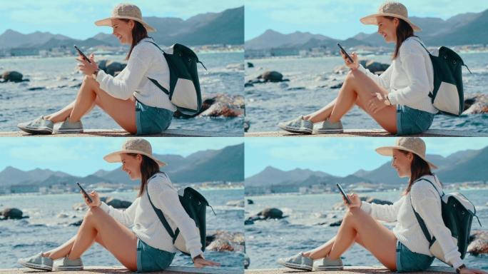 4k视频片段，一位快乐的年轻女子一边在海边放松一边用手机发短信