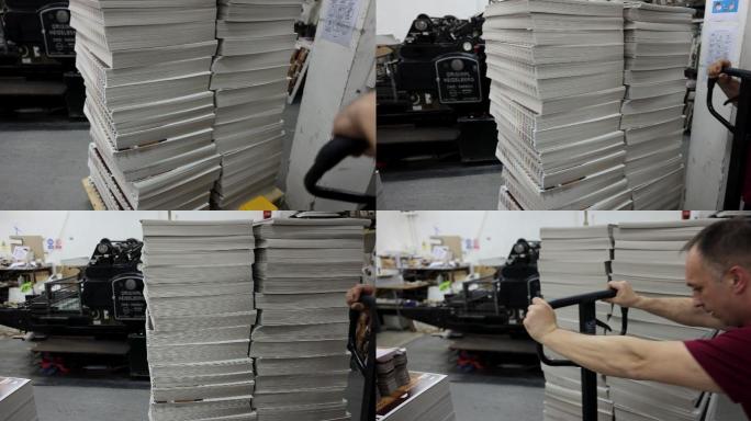 专门的高加索人工人，用堆叠的印刷媒体拉动和推动手动叉车，以便交付订单