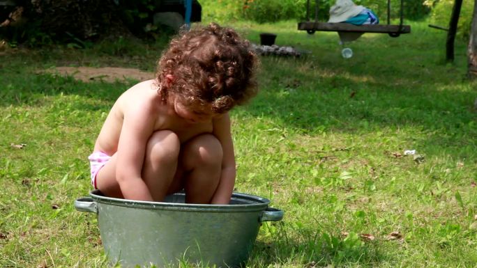快乐的孩子在金属盆里玩水