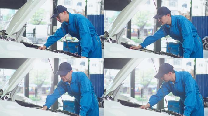 亚洲汽车修理工在修理厂工作时戴头盔。年轻的车辆服务经理男性工人打开汽车引擎盖，然后在车间进行检查和维