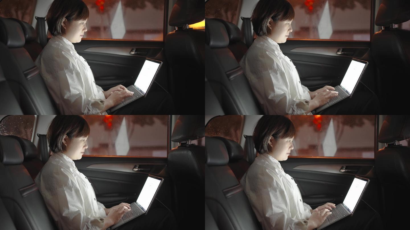 在汽车后座使用笔记本电脑的女性