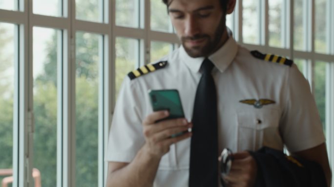 飞行员在机场航站楼使用智能手机