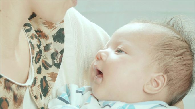 亚洲母亲在卧室里抱着并亲吻着混血可爱的新生女婴的额头