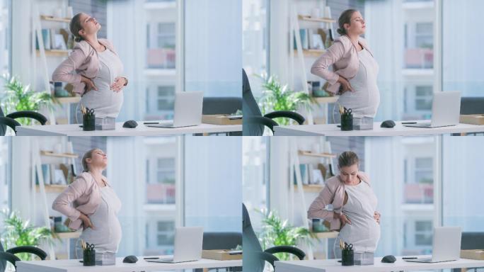 一名年轻孕妇在现代办公室使用笔记本电脑时背部疼痛的4k视频片段