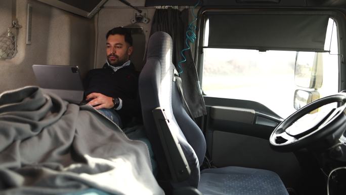 卡车司机躺在驾驶室床上使用平板电脑