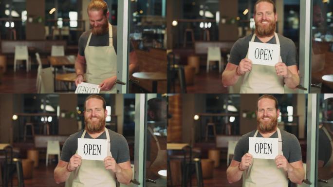 一名年轻男子在一家咖啡馆入口处举着一块开放式标牌的4k视频片段