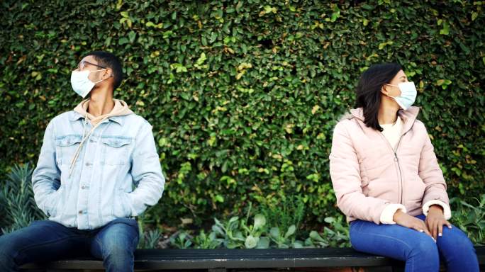 一对戴面具的年轻男女在公园里约会时分开坐着的4k视频片段