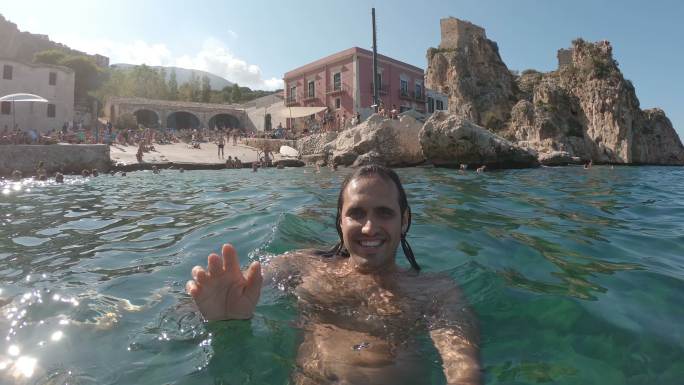 千禧一代男子在西西里岛斯科佩罗游泳时正在进行视频通话
