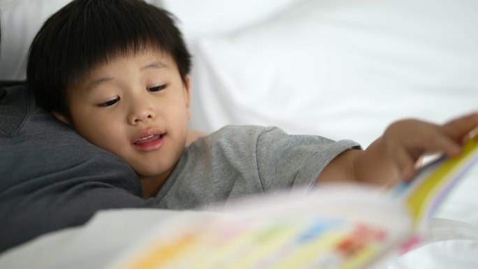 亚洲孩子和妈妈在卧室里读《睡前故事》。家庭时间的概念
