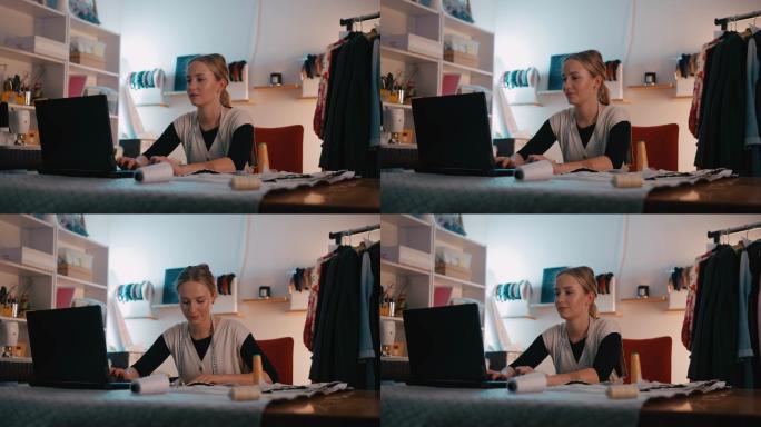 DS年轻女裁缝在工作室里用笔记本电脑工作