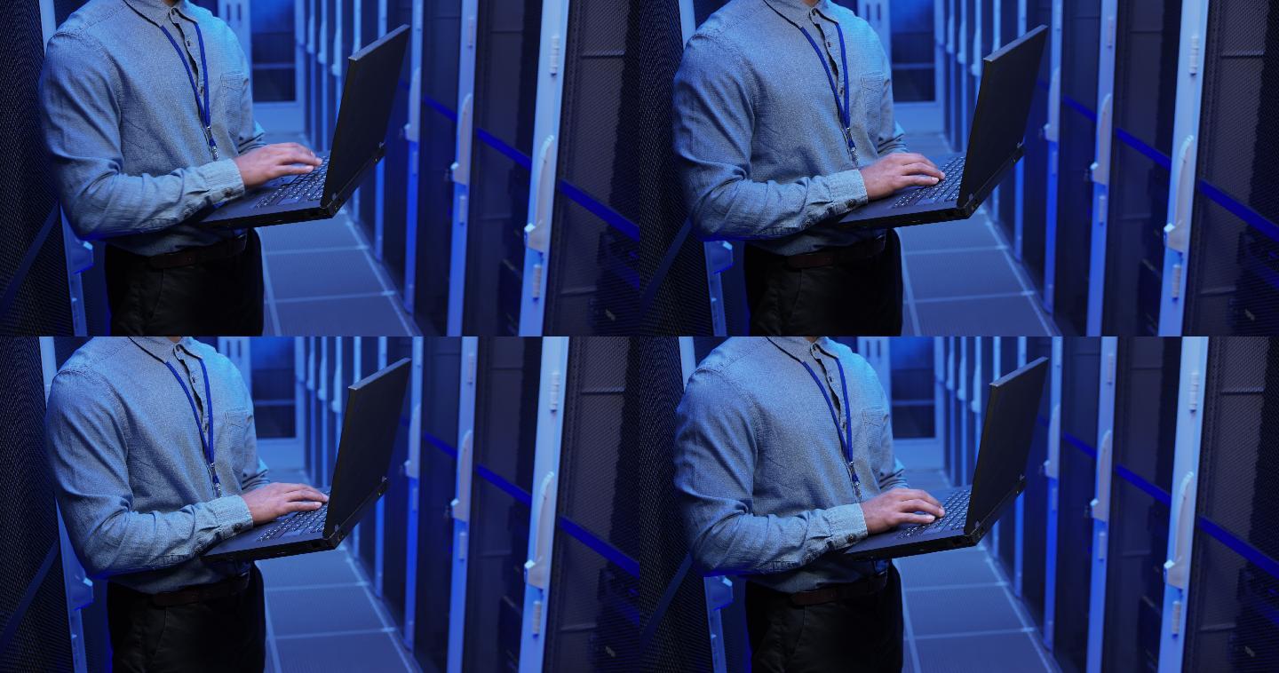 LD男性网络工程师站在服务器机房内使用笔记本电脑