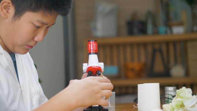 亚洲男孩在实验室里用显微镜检测外套，在家庭学校的实验室里，教育生活方式的理念。