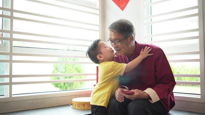 中国农历新年期间，一名亚裔中国孙子在客厅拥抱祖父
