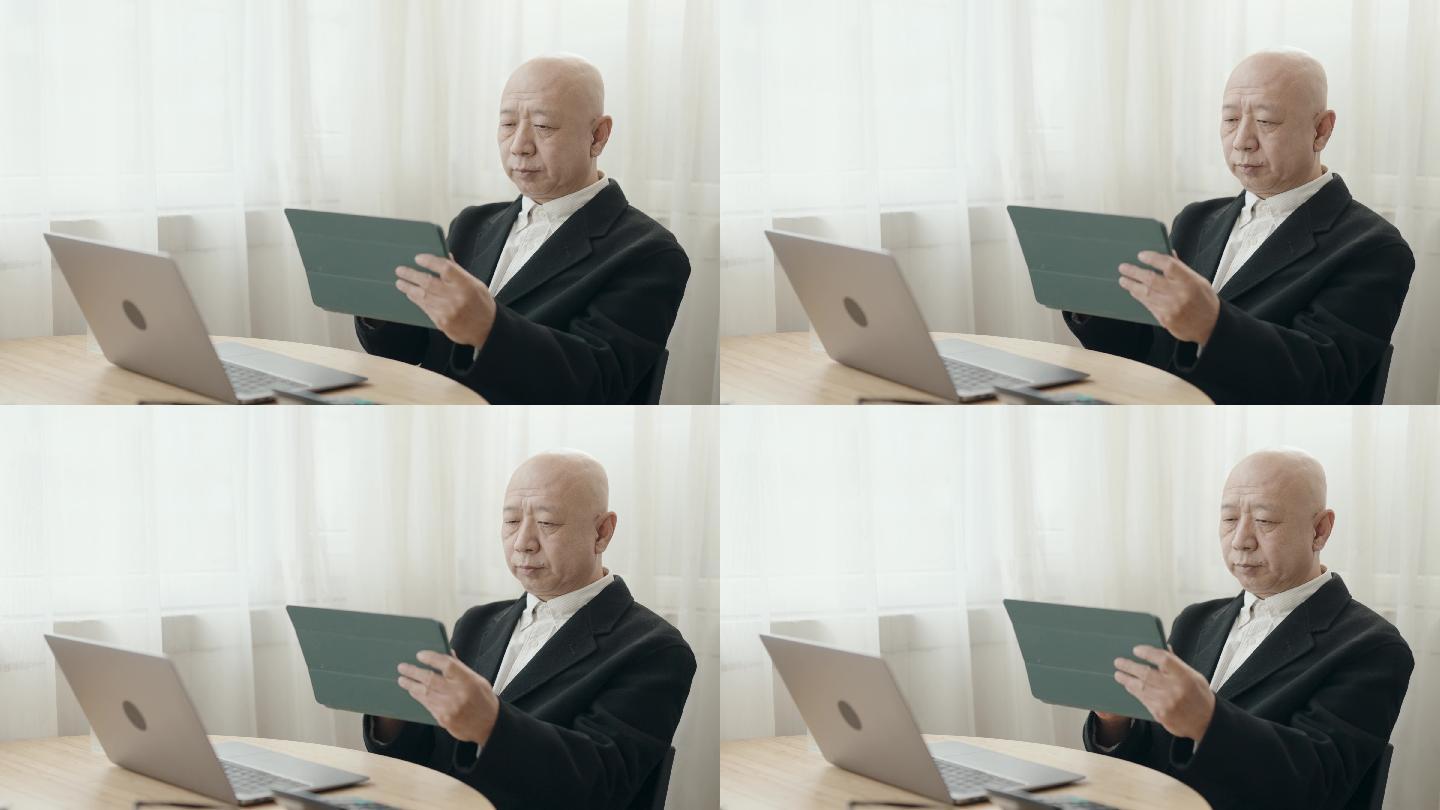 亚裔华裔无发老人使用笔记本电脑打字在开放式办公室工作