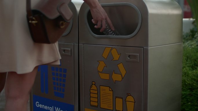 用手将塑料瓶扔进垃圾桶