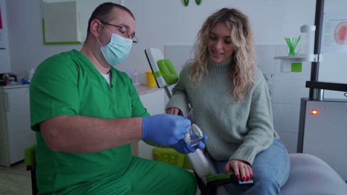 牙医向他的女性患者展示如何正确清洁牙齿