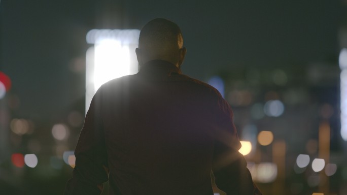 一名男子夜间在城市屋顶上的4k视频片段