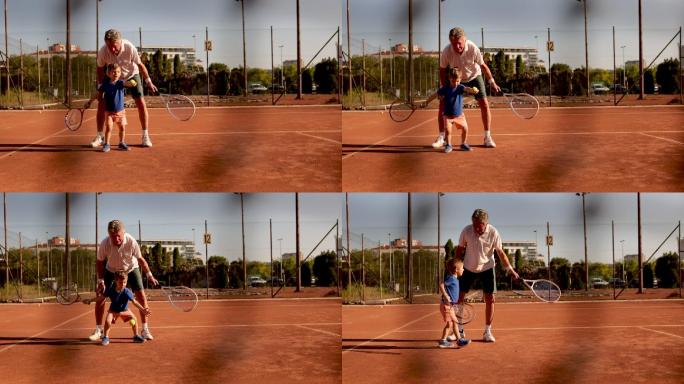 骄傲的爷爷在网球练习时与他可爱的孙子交换了hige five