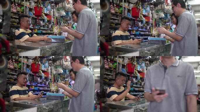 亚裔中国车主正在处理二维码阅读器，客户使用智能手机点击付款