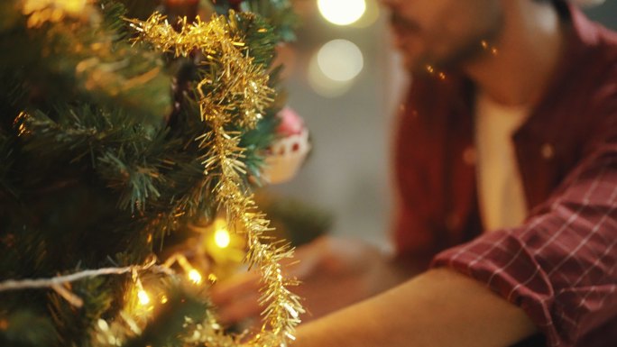 男人装饰圣诞树并在晚上庆祝