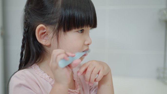 亚洲可爱的小女孩或小孩在浴室用牙刷刷牙。牙科卫生保健概念。
