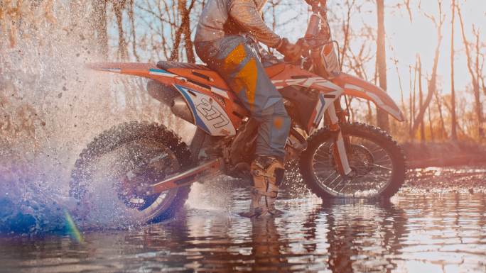 超级SLO MO摩托车越野赛骑手在水坑中转弯摩托车