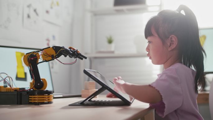 一个女孩正在学校玩机器人手臂。他正在用手控制它。