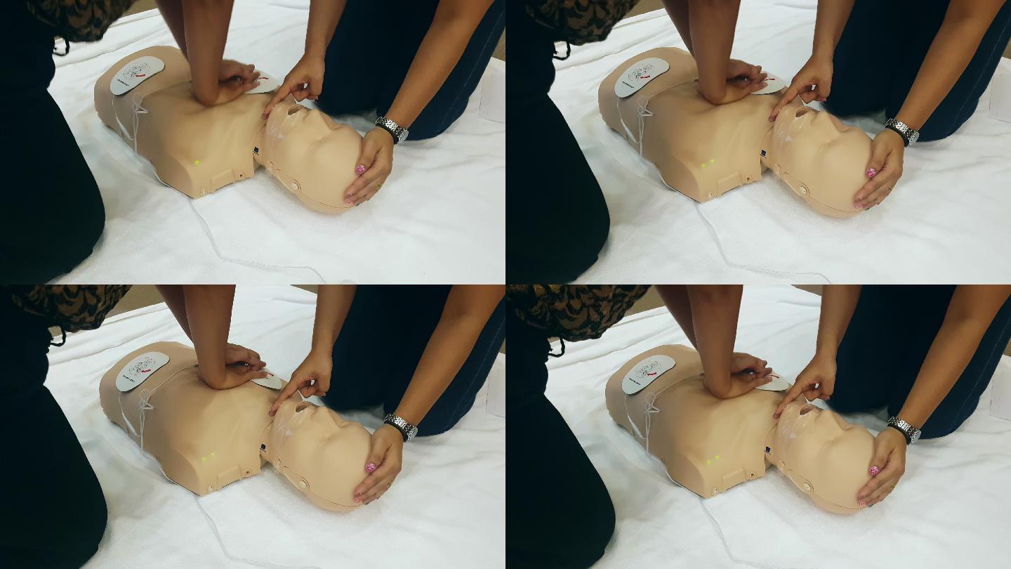 学生学习如何使用CPR玩偶和AED机在CPR培训班的紧急情况下抢救患者