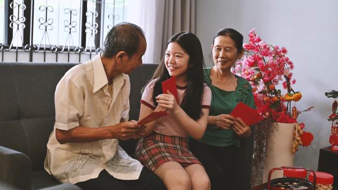 农历新年期间，亚洲孙女在客厅迎接并接受祖父母的春节红包（Angpow）