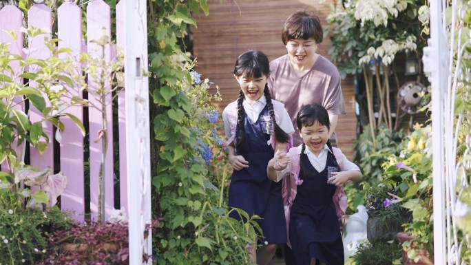 早上，一位亚裔中国母亲在家门口送两个女儿上学