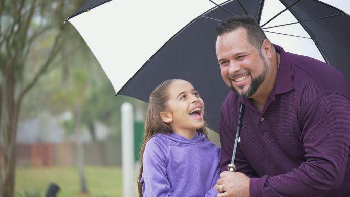 西班牙裔女孩，父亲雨天在雨伞下聊天