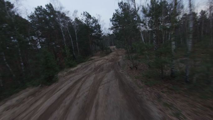 黄昏的摩托车越野赛。驾驶员在越野地形上超速行驶。FPV-赛车无人机视图。驱动程序POV