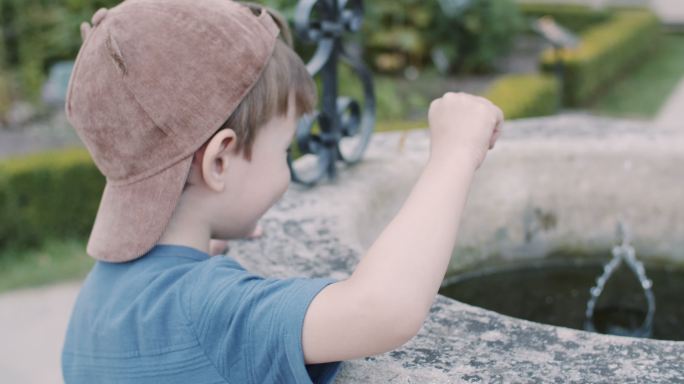 可爱的小游客往喷泉或水井里扔硬币