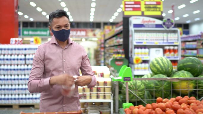 成熟男子戴口罩在超市买水果